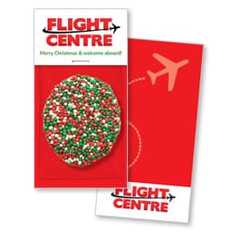 A festive Christmas card featuring red, green, and white sprinkles on a chocolate treat, with a logo.