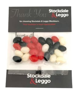 A plastic package containing an assortment of red, black, white, and pink jelly beans.