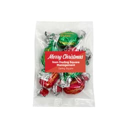 A clear bag of Christmas toffees featuring green and red wrapped sweets. The bag has a logo and festive message.