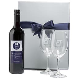 A wine bottle with a custom label and two engraved glasses, presented in a silver gift box with a navy ribbon.