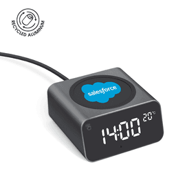 A grey wireless charger and alarm clock made from recycled aluminium, featuring a logo and displaying the time and temperature.