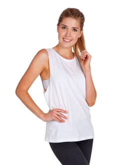 A woman stands wearing a white sleeveless tank top, styled with a relaxed fit, paired with dark pants.