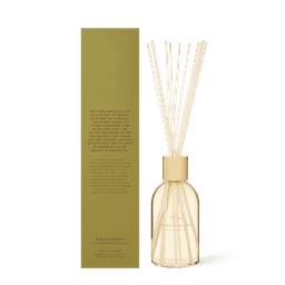 A diffuser with a clear glass bottle, pale yellow cap, and reed sticks, featuring a soft fragrance of camellia and lotus.