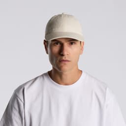 A beige cap worn by a model, featuring a front-panel design and a logo. The model is dressed in a white T-shirt.