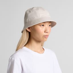 A light grey bucket hat sits on a model's head, featuring a simple design and a logo.