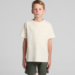 A neutral cream youth T-shirt with short sleeves, paired with dark green shorts. The shirt features a logo.