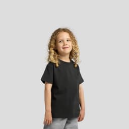 A child wearing a black heavy faded tee, paired with grey shorts, smiling at the camera.