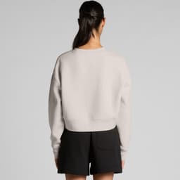 A light grey crop crew jumper viewed from the back, paired with black shorts. The design features a simple silhouette and a logo.