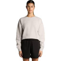 A cropped, light grey jumper with a relaxed fit, paired with black shorts. The model stands with arms by her side.