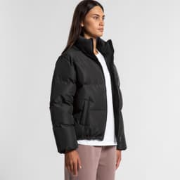 A black puffer jacket with a high collar and side pockets, worn by a model standing against a neutral background.