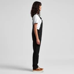Black canvas overalls worn with a white T-shirt and brown shoes, displayed in a side view. The outfit features a logo.