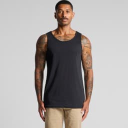 A man stands wearing a plain black singlet, showcasing its simple design and fit. The singlet has a logo.