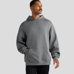 A grey hoodie with a kangaroo pocket and a hood, worn by a man standing against a plain background.
