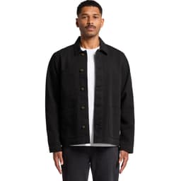 A man wearing a black canvas chore jacket with front pockets, styled over a white t-shirt.