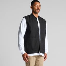 A black canvas heavy vest worn over a white long-sleeve shirt, featuring two front pockets and a zip closure.