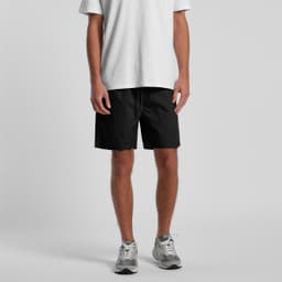Black sports shorts with an elastic waistband, modelled by a person wearing a white t-shirt and grey sneakers.