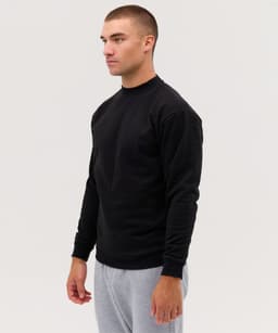 A black jumper with long sleeves, featuring a fitted design and a logo on the front, worn by a model.