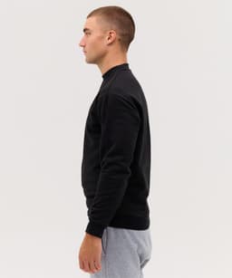 A black hoodie displayed on a male model, featuring a simple design and ribbed cuffs.