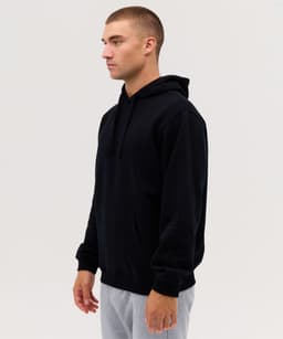 A black hoodie with a front pocket and drawstring hood, displayed on a model in profile view.