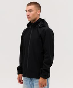 A man wearing a black Core Weather Jacket stands against a neutral background. The jacket features a hood and has a logo.