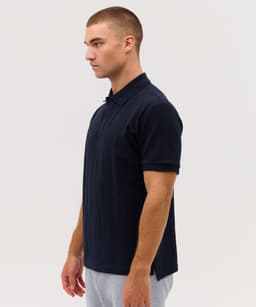A navy Delta Polo shirt with a collar, shown from the side, featuring a simple design and a logo.