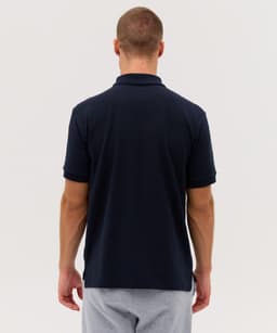 A navy blue polo shirt with a classic design and a logo on the back, displayed on a model.