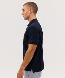 A navy blue polo shirt displayed on a model, featuring a collar and a side view. The shirt has a logo on it.