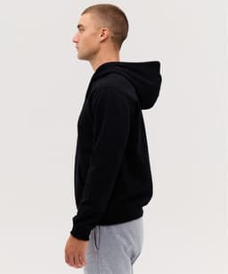 A black hoodie with a kangaroo pocket, featuring a hood, modelled by a person in profile.