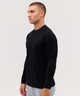 A long sleeve black tee worn by a model, featuring a fitted design and a logo on the sleeve.