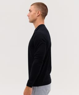 A black long sleeve tee featuring a crew neck and fitted design, showcased on a model in profile view.