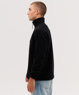 A black polar fleece 1/4 zip jacket displayed on a model from the side, featuring a zip collar and a branding logo.