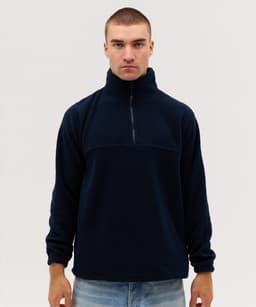 A navy blue polar fleece 1/4 zip jacket with a high collar and long sleeves. The product has a logo.