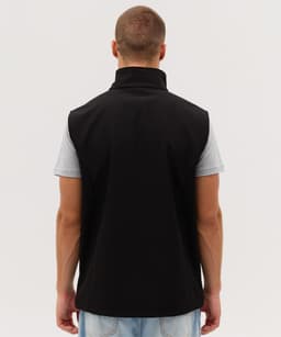 A black softshell vest with a high collar, viewed from the back, featuring a logo on the side.