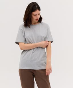 A grey t-shirt with short sleeves displayed on a model, featuring a simple design and a relaxed fit.