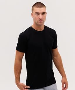 A plain black t-shirt on a model, featuring a slim fit and short sleeves. The model has short hair and a neutral expression.