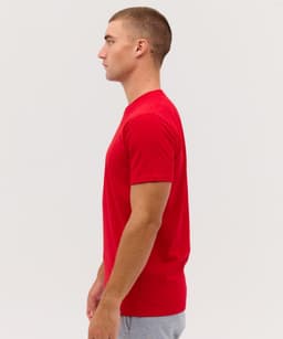 A red T-shirt displayed on a male model, showing the side view. The shirt features a logo on the chest.