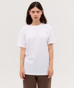 A plain white T-shirt with short sleeves, displayed on a model against a neutral background.