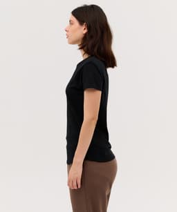 A black women's essential tee displayed on a model from the side, highlighting its simple design.