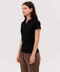 A black women's polo shirt with short sleeves and a zippered front, featuring a minimalist design.
