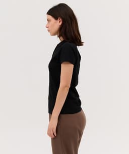 A side view of a black women's polo shirt, featuring a fitted design and short sleeves. It has a logo on the chest.