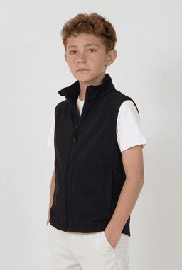 A black softshell vest featuring a zip front and stand collar, worn by a child. The vest has a logo on it.