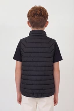 A black puffer vest with a high collar, viewed from the back, worn over a black shirt.