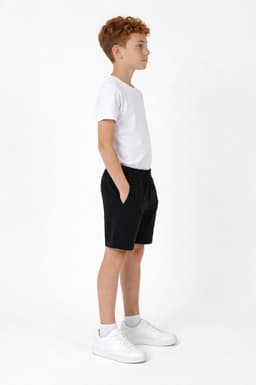 Youth Core Shorts in black, featuring side pockets, paired with a plain white t-shirt and white sneakers.