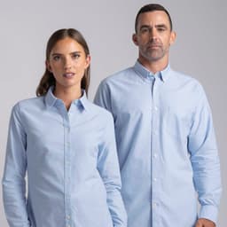 A light blue button-up shirt for women with a single pocket and a classic collar, featuring a logo.