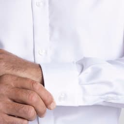 A men's white button-up shirt with a close-up of the cuff and buttons, featuring a logo.
