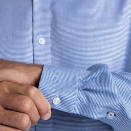 A blue check patterned button-up shirt with white buttons, showing a close-up of the sleeve and cuff.