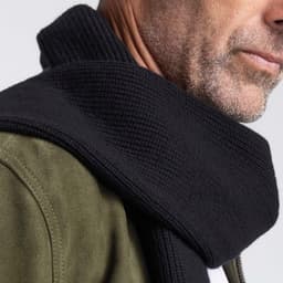 A black 100% Merino scarf with a textured knit, draped around the neck of a model.
