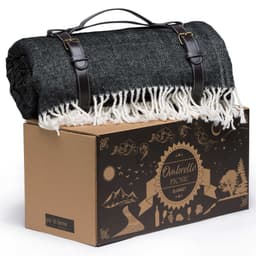 A rolled black and white herringbone picnic blanket with leather straps sits atop a decorative box.
