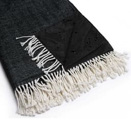 A green and black picnic blanket with a herringbone pattern and white fringes, featuring a water-resistant corner.