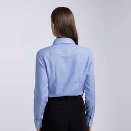 A women's button-up shirt in light blue, featuring a collar and long sleeves, with a branding logo on the back.
